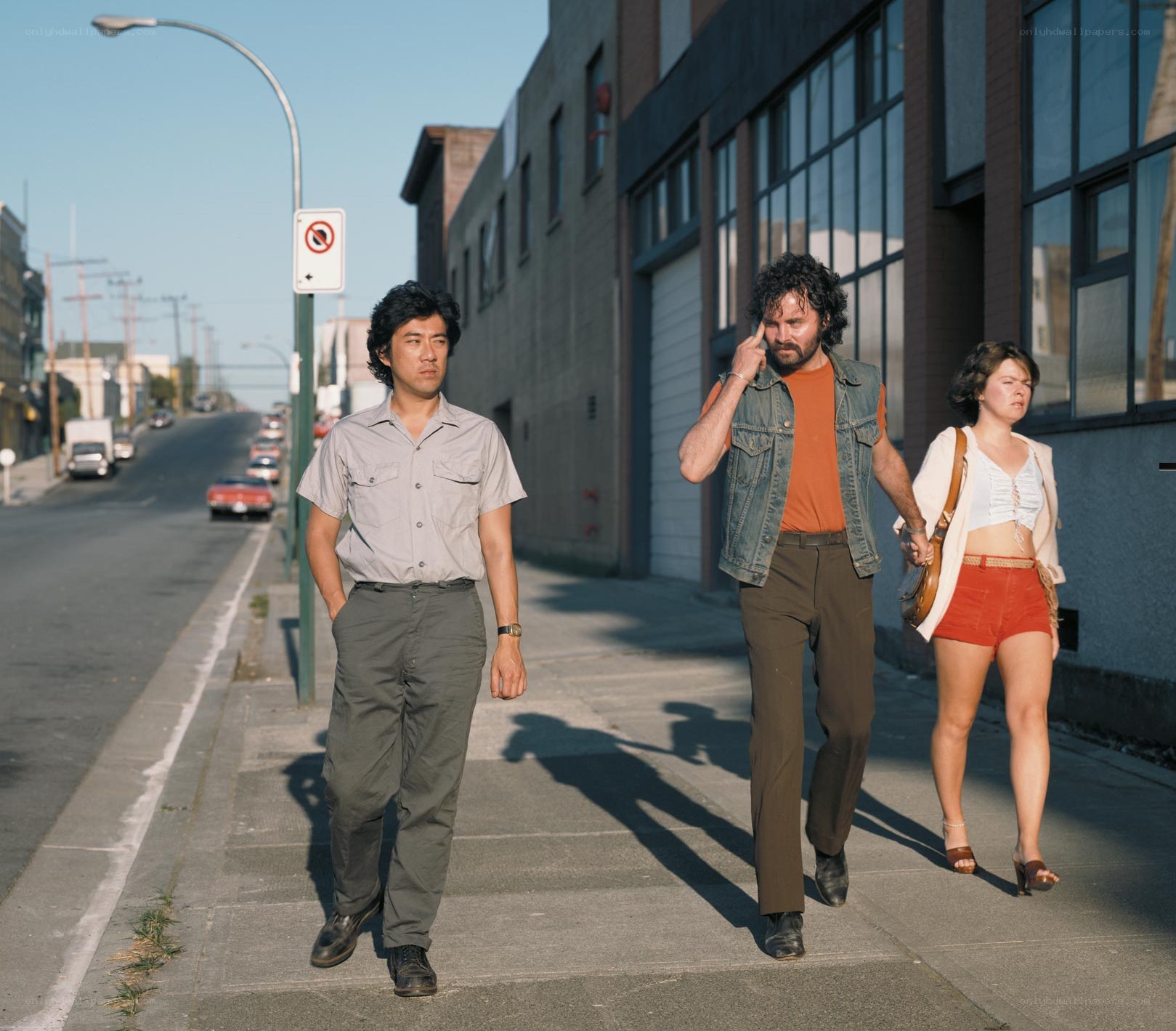 Three people walking on a sidewalk