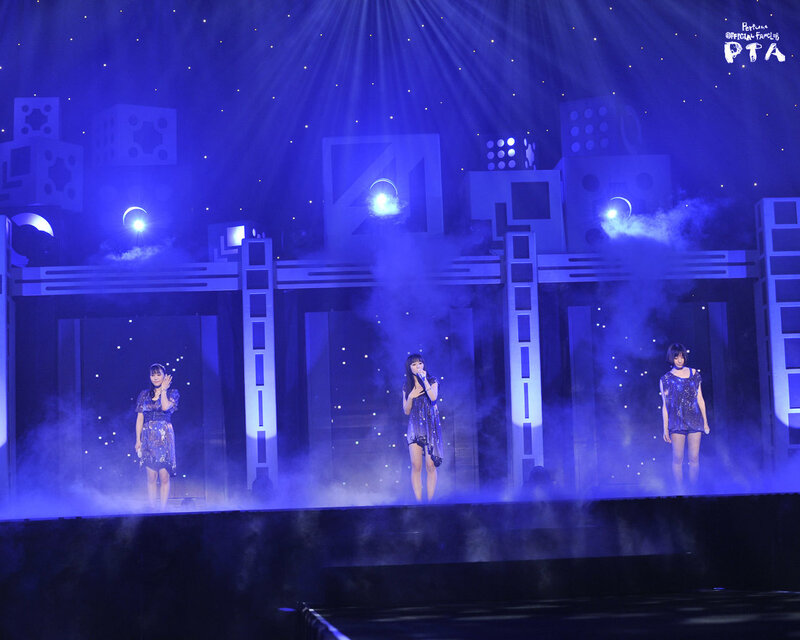 Three performers on a blue-lit stage