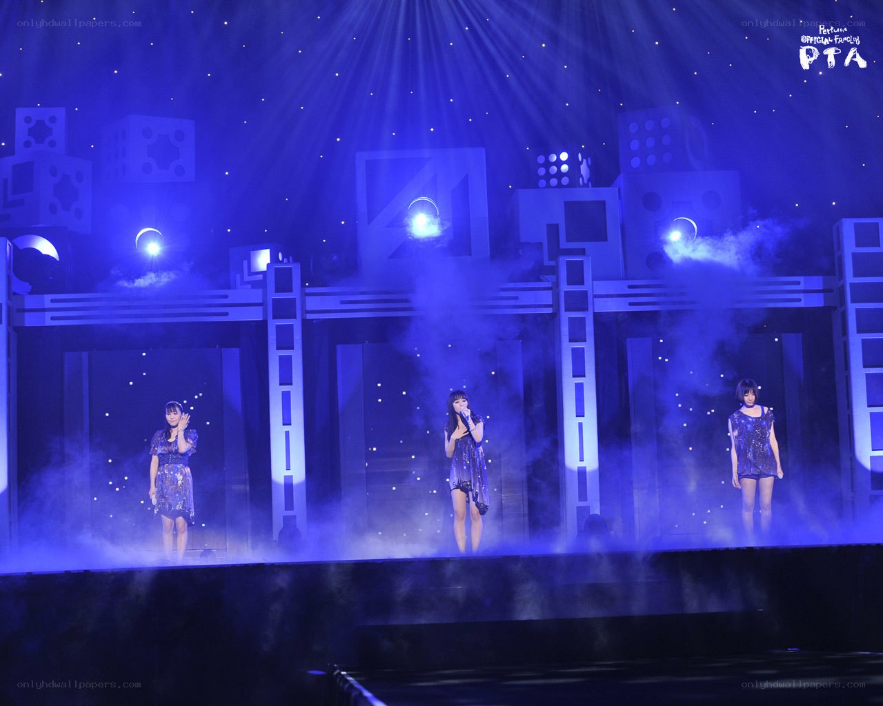 Three performers on a blue-lit stage