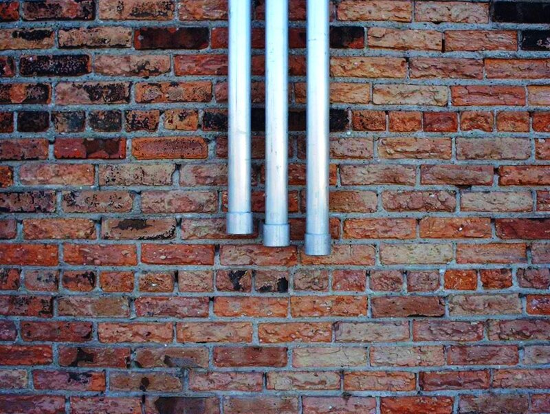 Three Pipes on Brick Wall