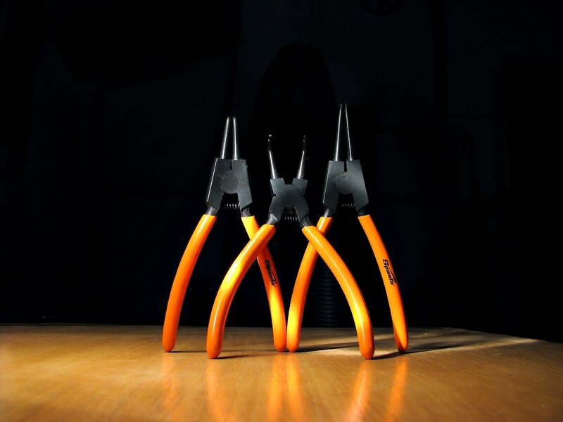 three pliers on wooden surface