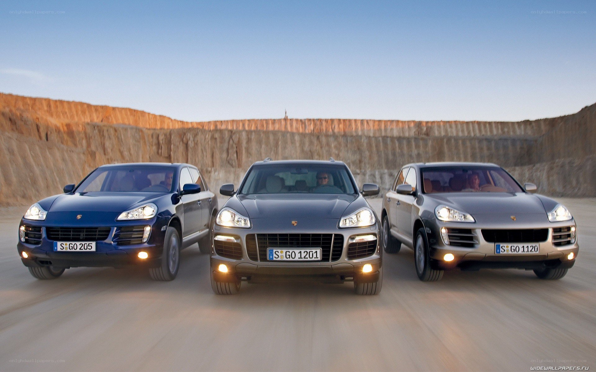 Three Porsche Cayenne SUVs on a road
