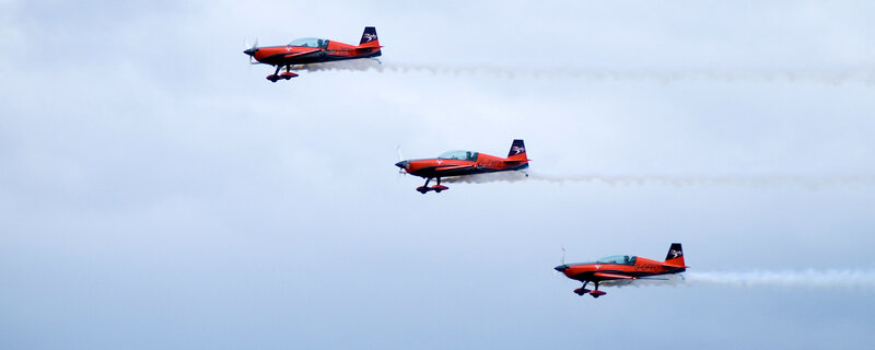 Three red aerobatic planes in formation