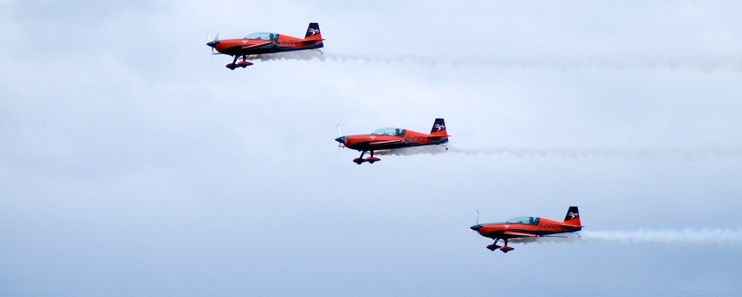 Three red aerobatic planes in formation