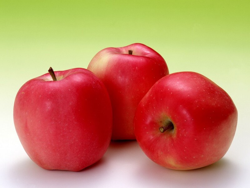Three red apples on green