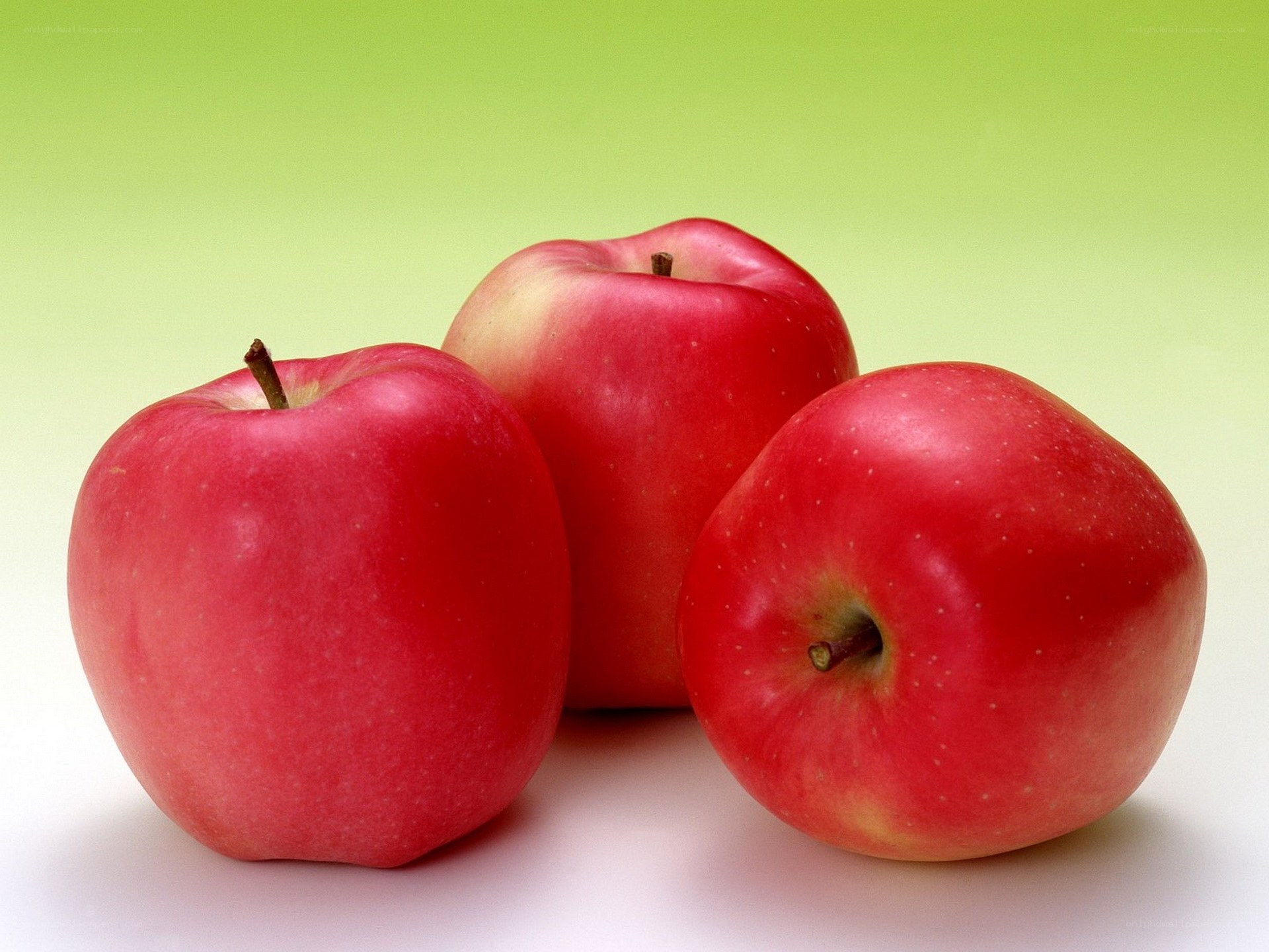 Three red apples on green