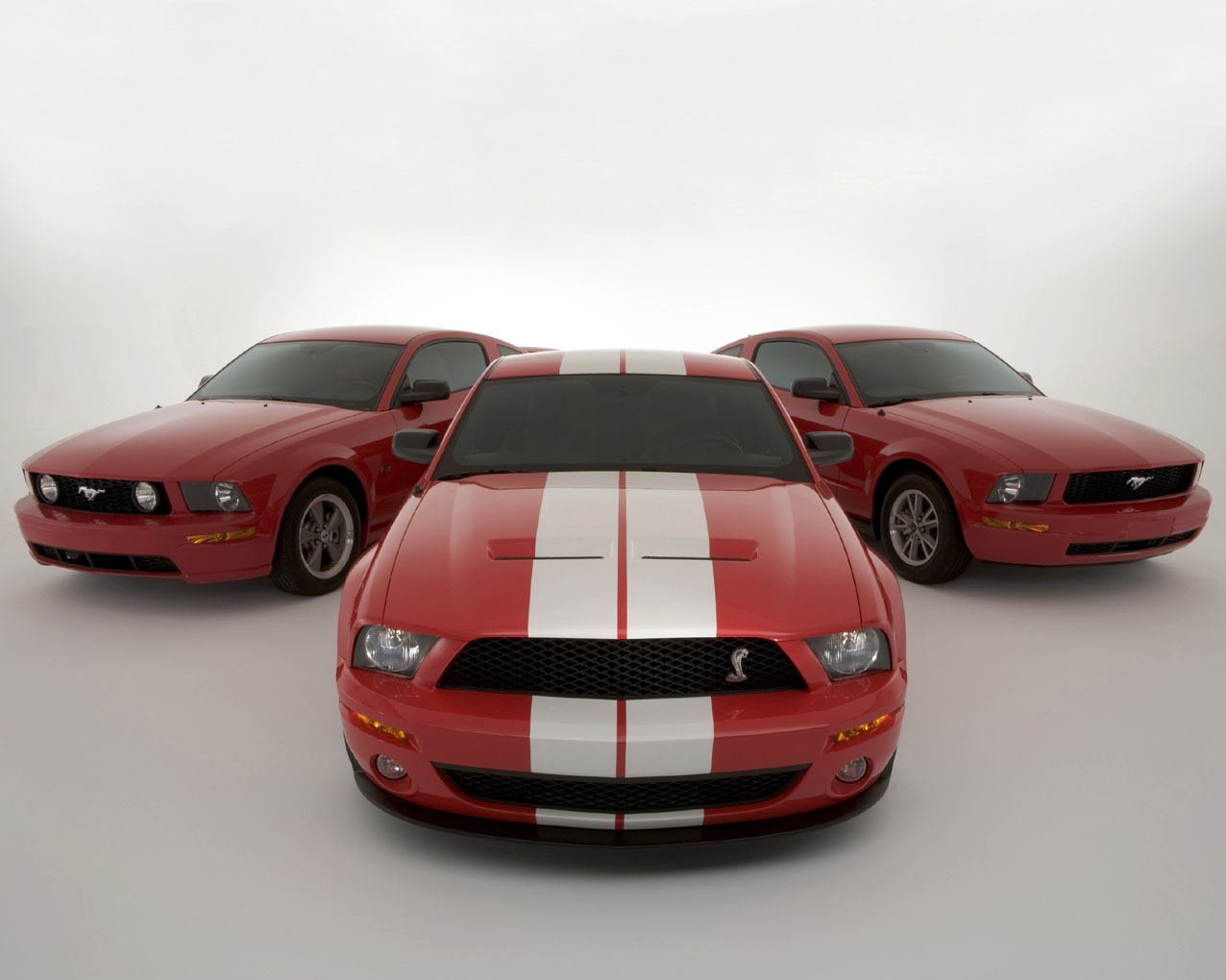 Three red Ford Mustangs