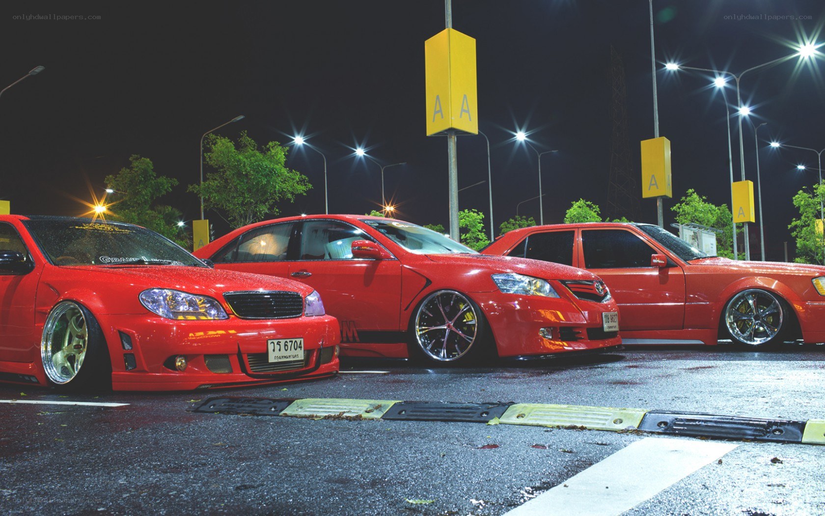 Three red modified cars at night