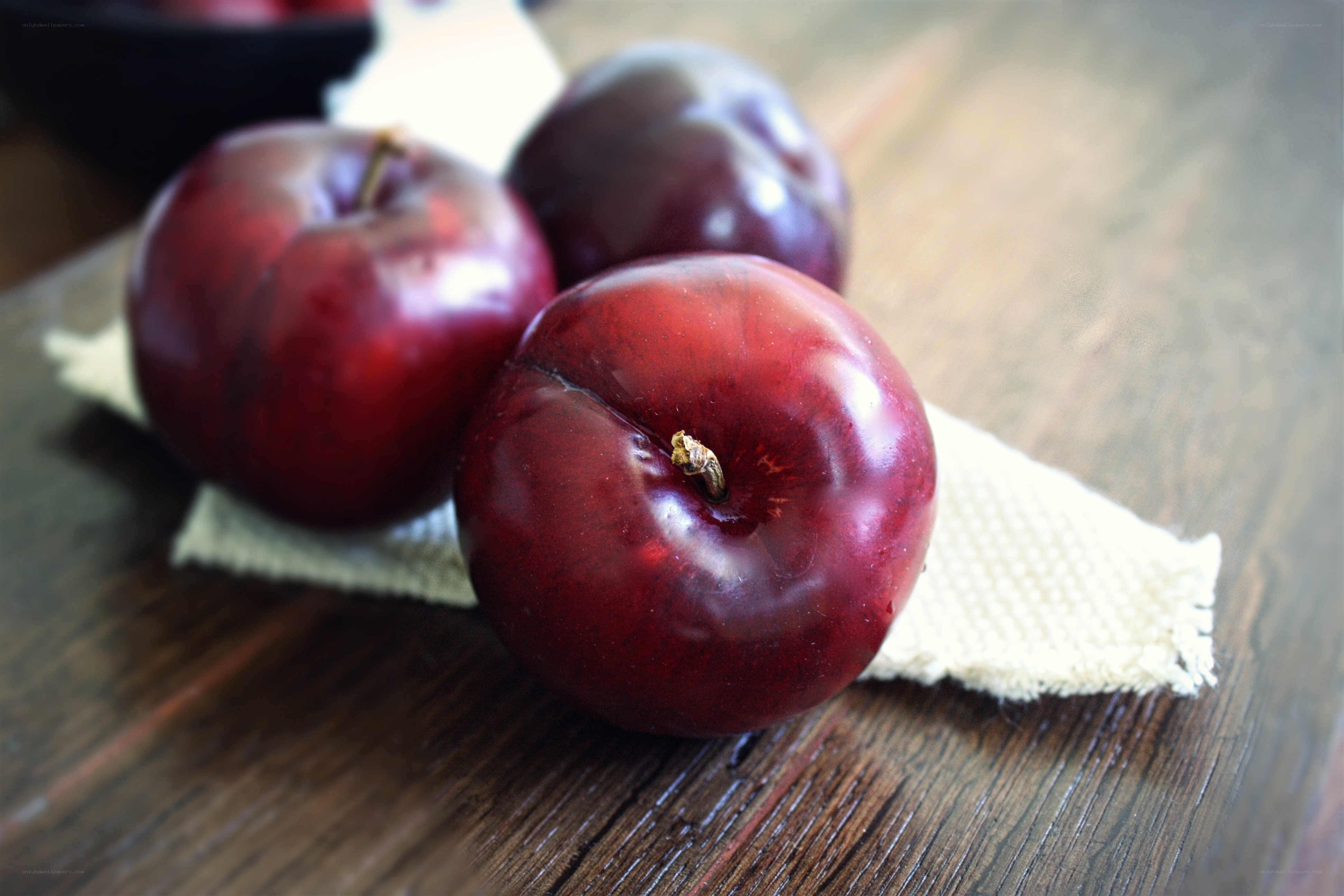 Three red plums on a cloth