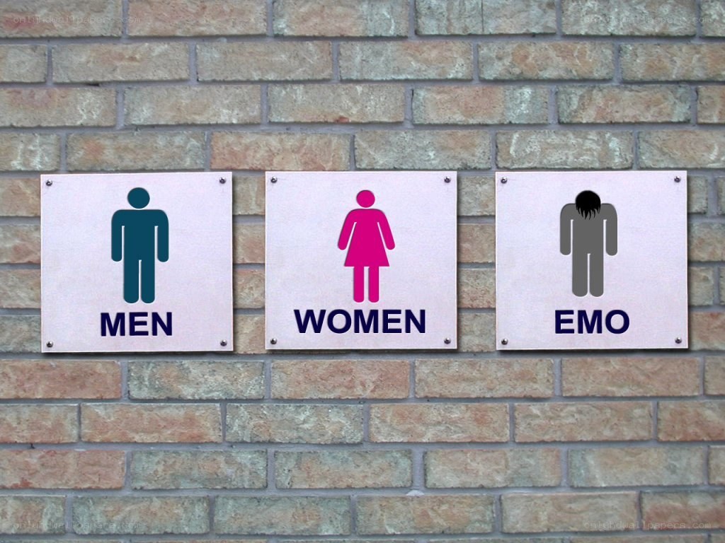 three restroom signs on a brick wall