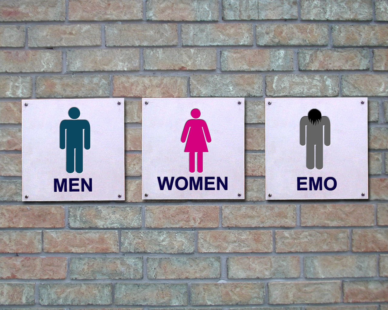 three restroom signs on brick wall