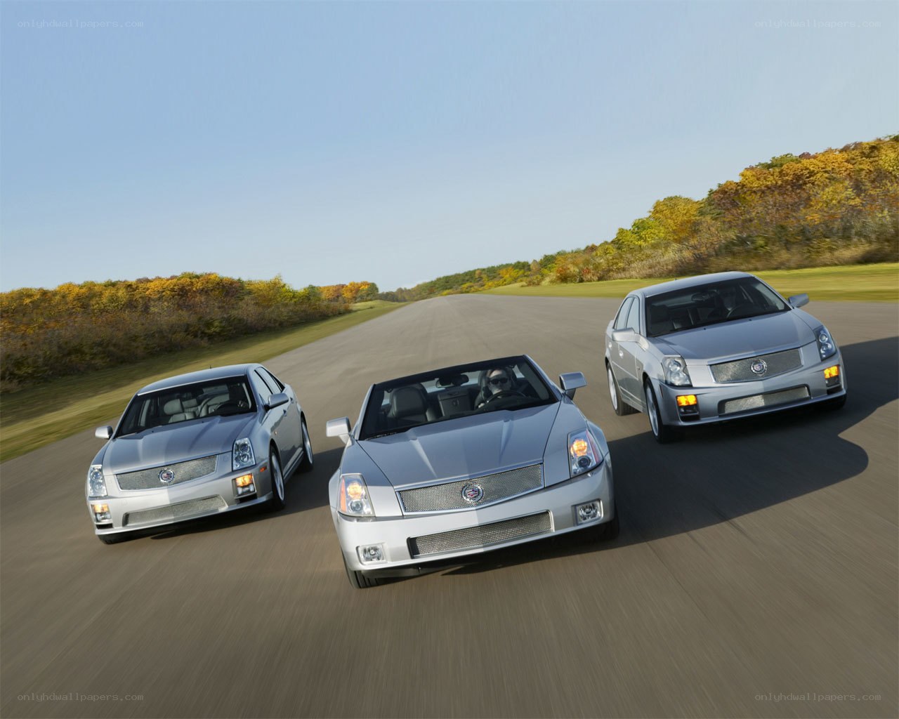 Three silver Cadillacs on a road