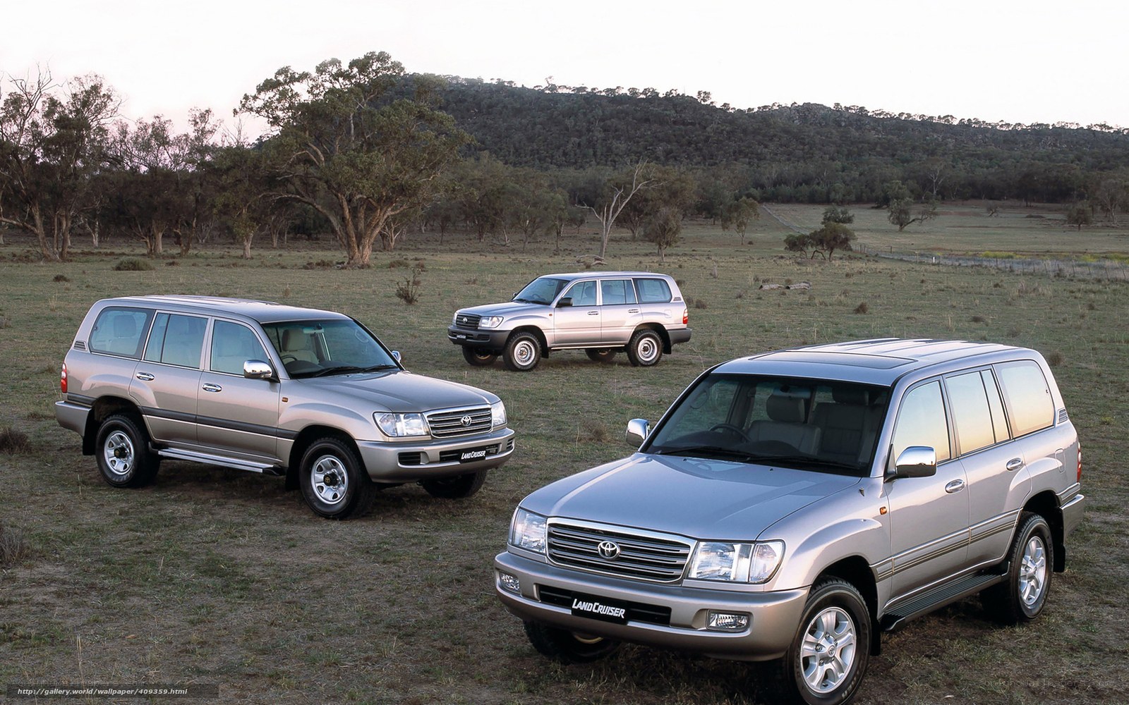 Three silver Land Cruisers in field