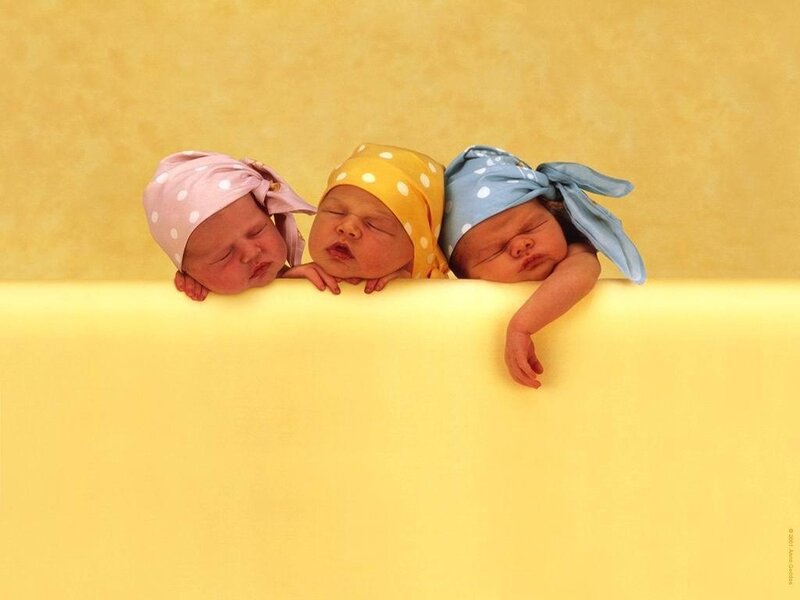 three sleeping newborns in hats