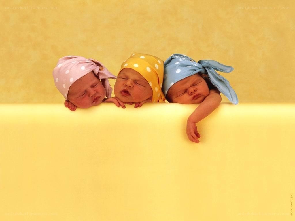 three sleeping newborns in hats