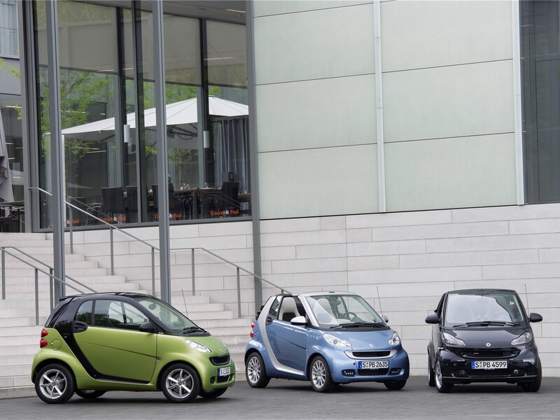 Three Smart cars in front of a building