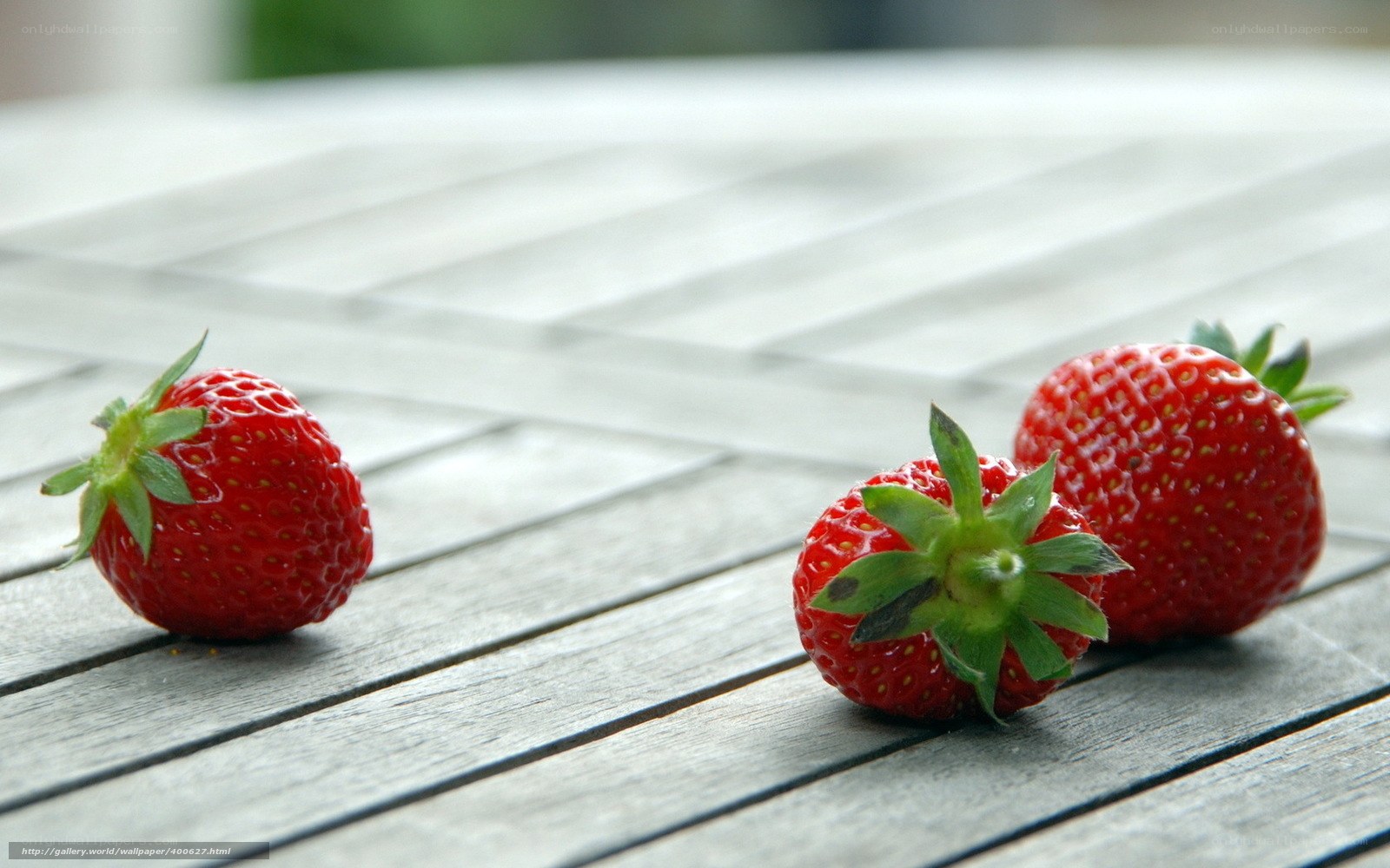 Three strawberries on a wooden table