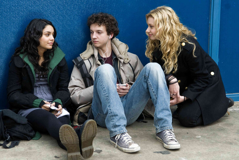 Three teens sitting on a sidewalk