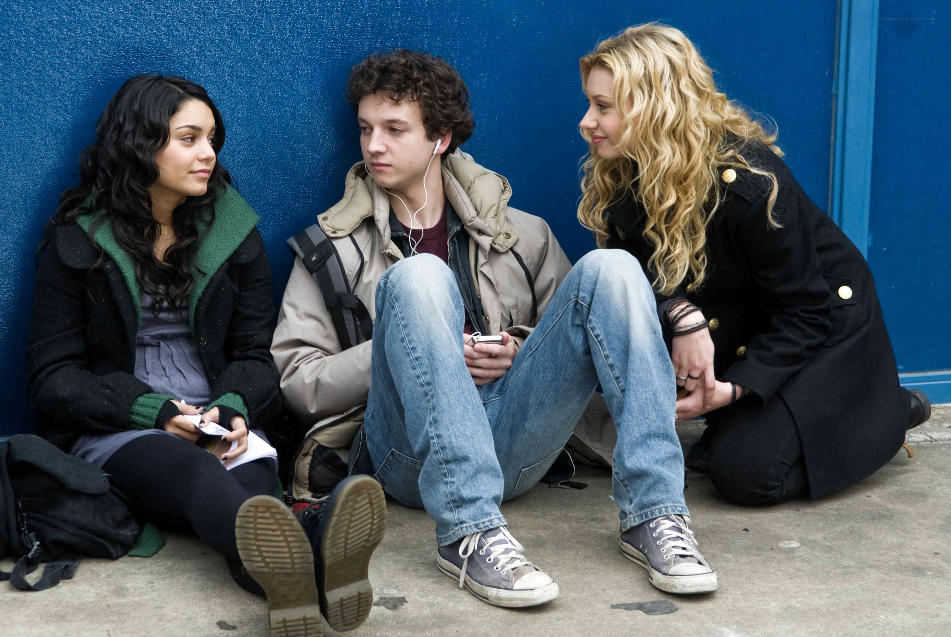 Three teens sitting on a sidewalk