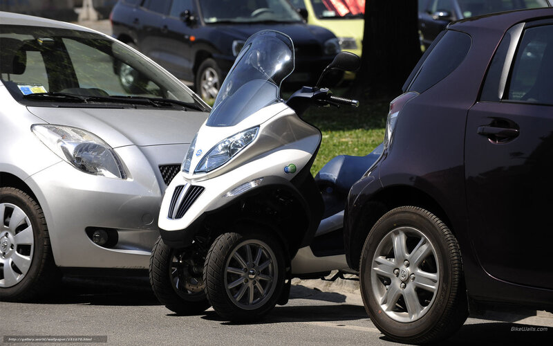Three-wheeled scooter parked between cars