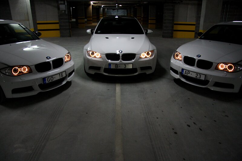 Three white BMWs in a garage