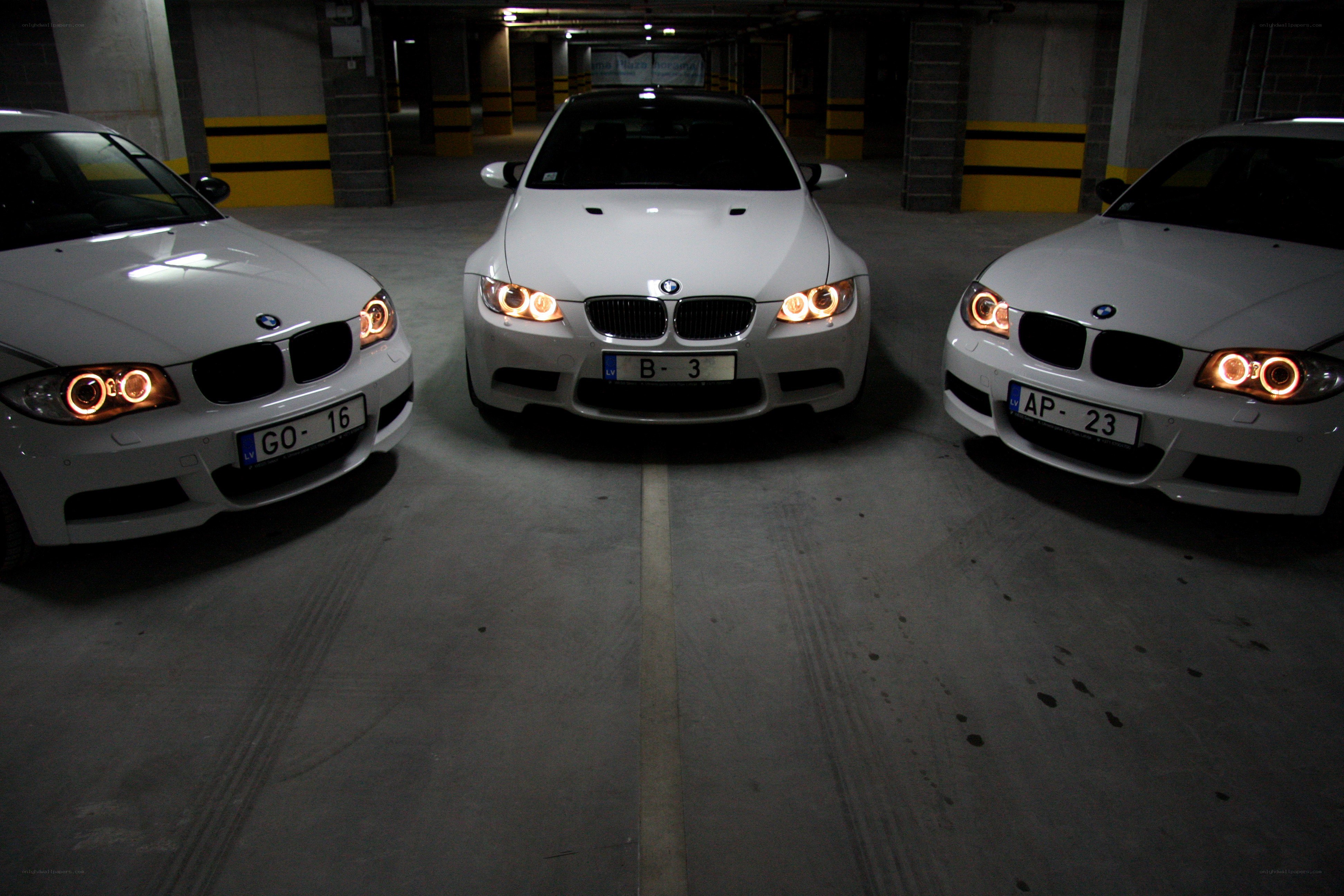 Three white BMWs in a garage