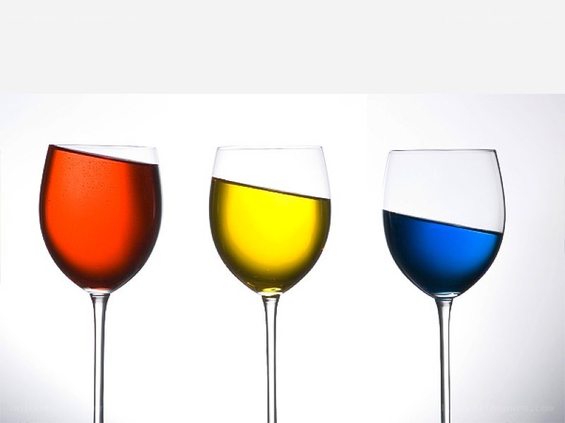 three wine glasses with colored liquids
