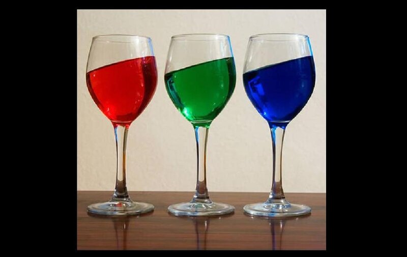 Three wine glasses with colored liquids