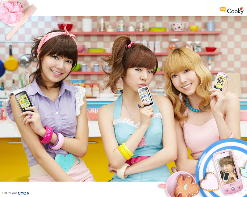 three women holding phones in kitchen