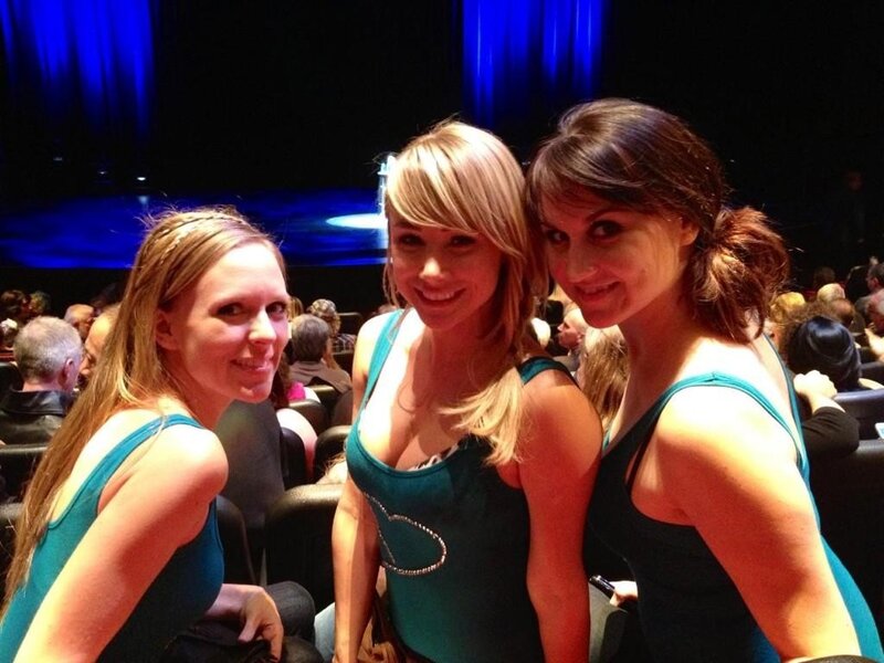 Three women in teal tops at a show