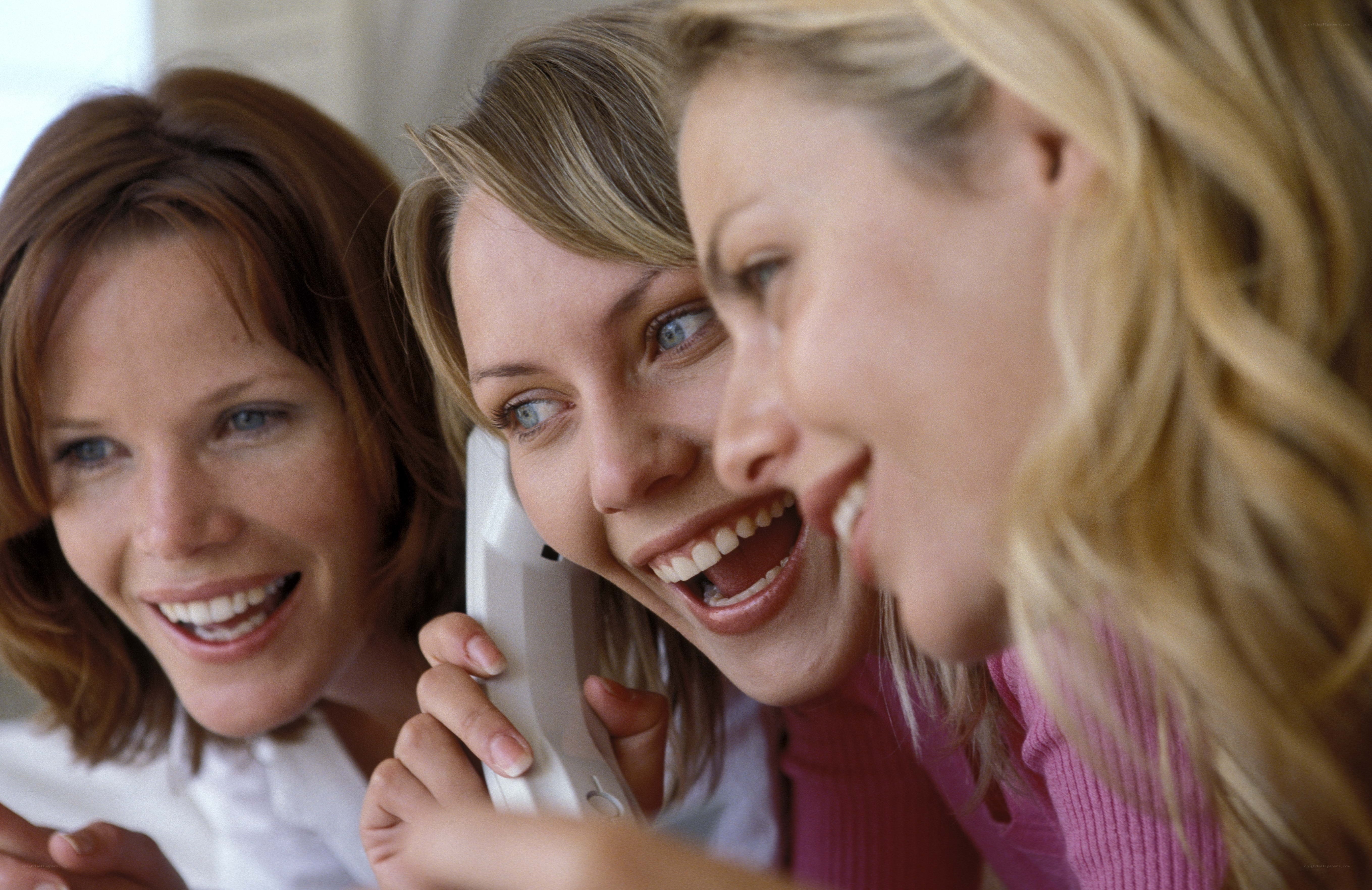 three women laughing on phone