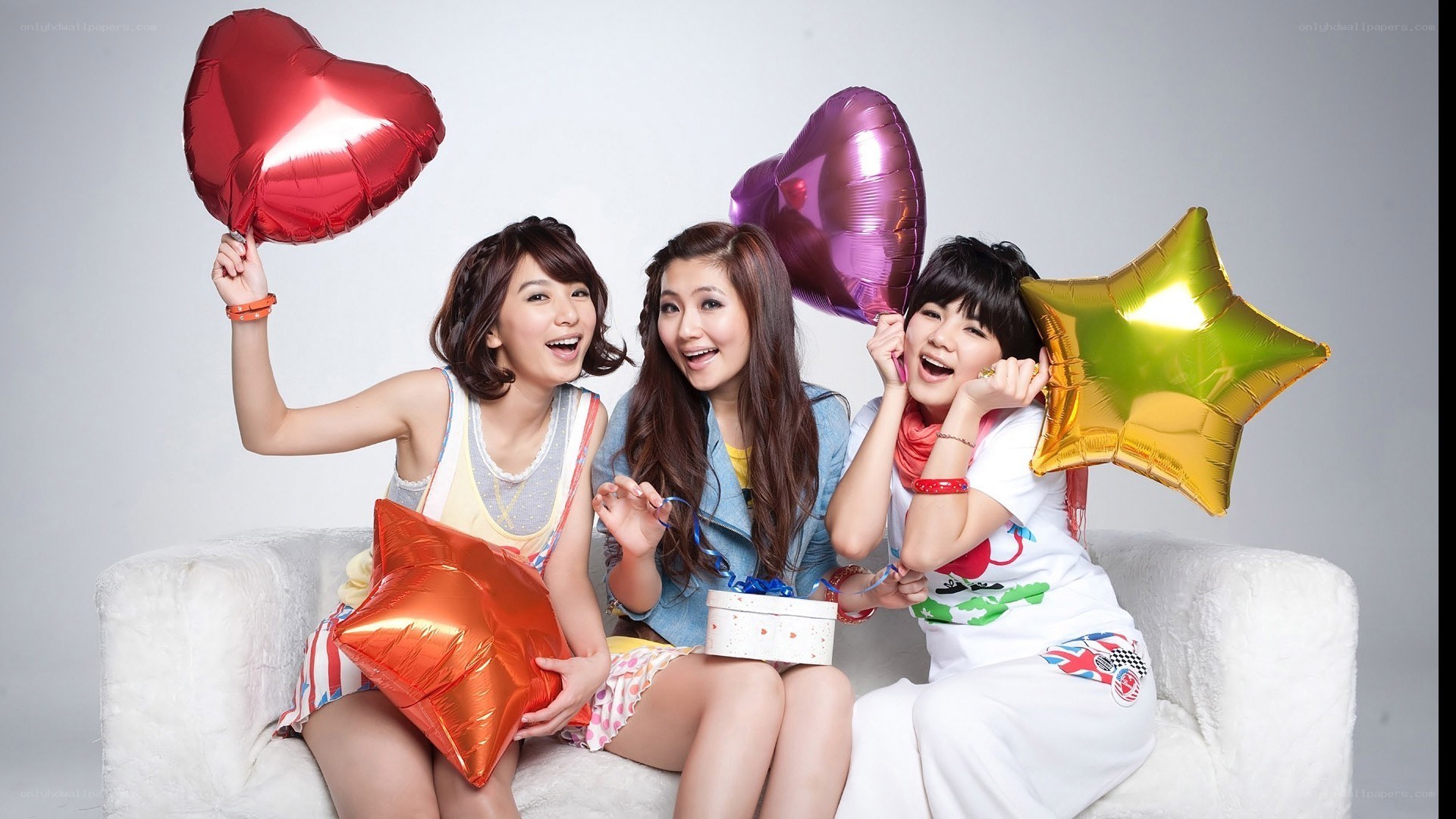 three women with balloons on couch