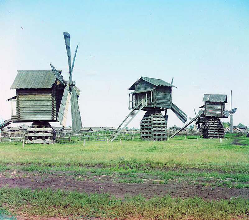Three wooden windmills in a field