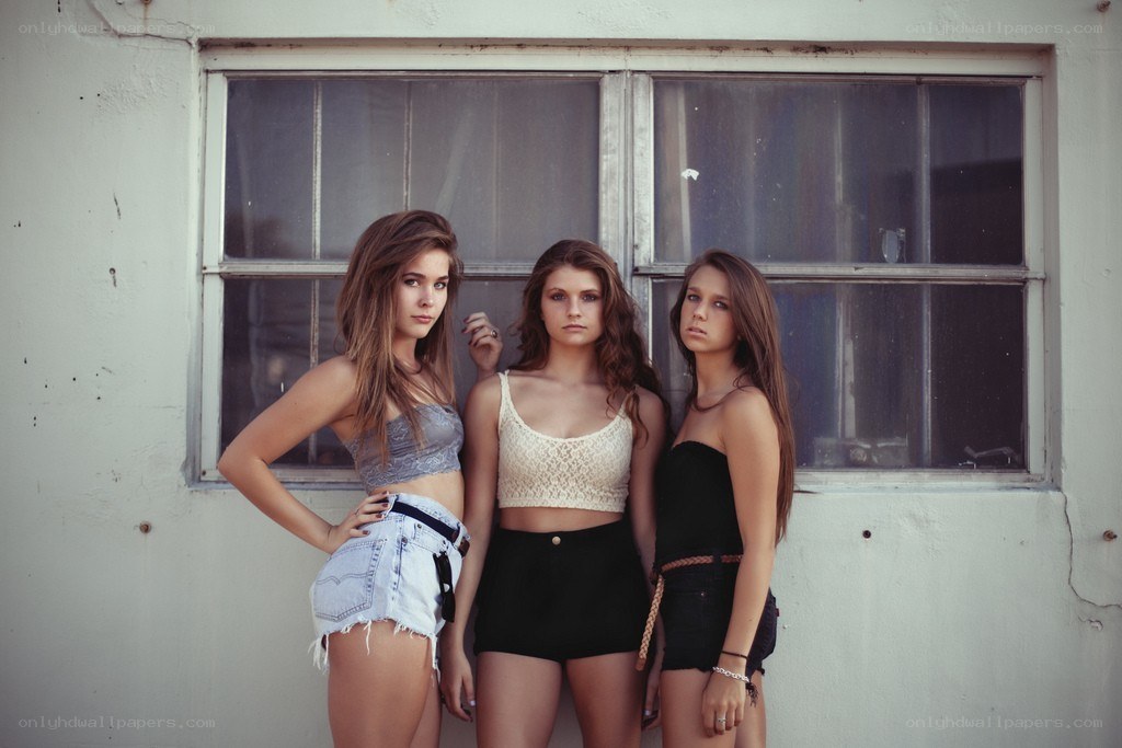 three young women posing by a window