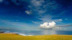 Blue clouds sky ocean land coast Green meadows