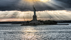 Liberty statue sun clouds