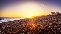 sky beach sunset contrails lens flare Sea stones orange sky