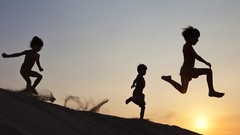Sunset sand children silhouettes jumping sand dunes