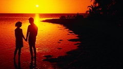 Sunset silhouettes couple holding