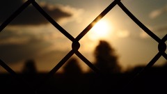 Sunset silhouettes fences blurred background Chain Link Fence