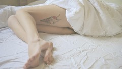 Woman beds legs tattoos