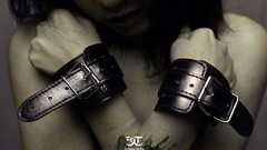 Woman belts cuffs artistic BDSM arms crossed
