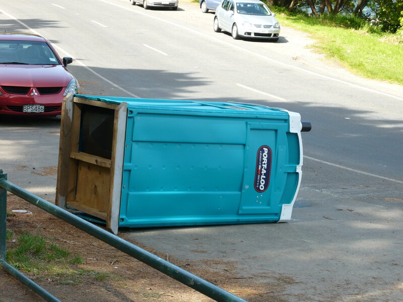 Tipped-over portable toilet on roadside
