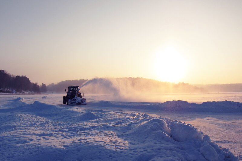 Tractor clearing snow at sunset