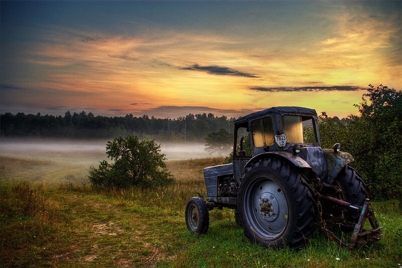 Tractor in a misty field at sunset