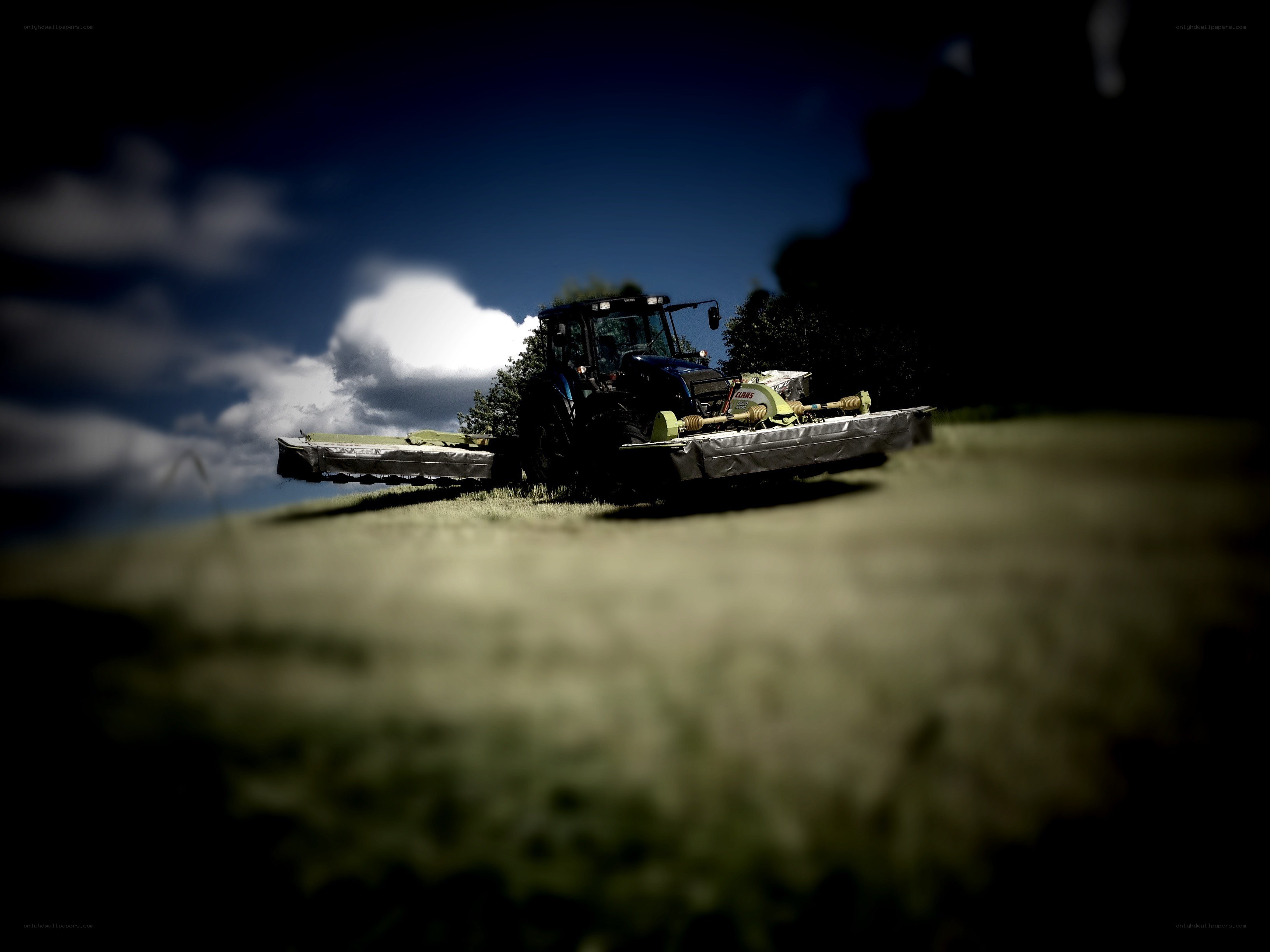 Tractor mowing field at dusk