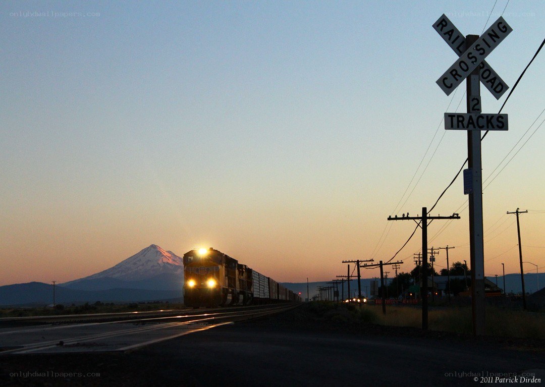 Train at railroad crossing with mountain