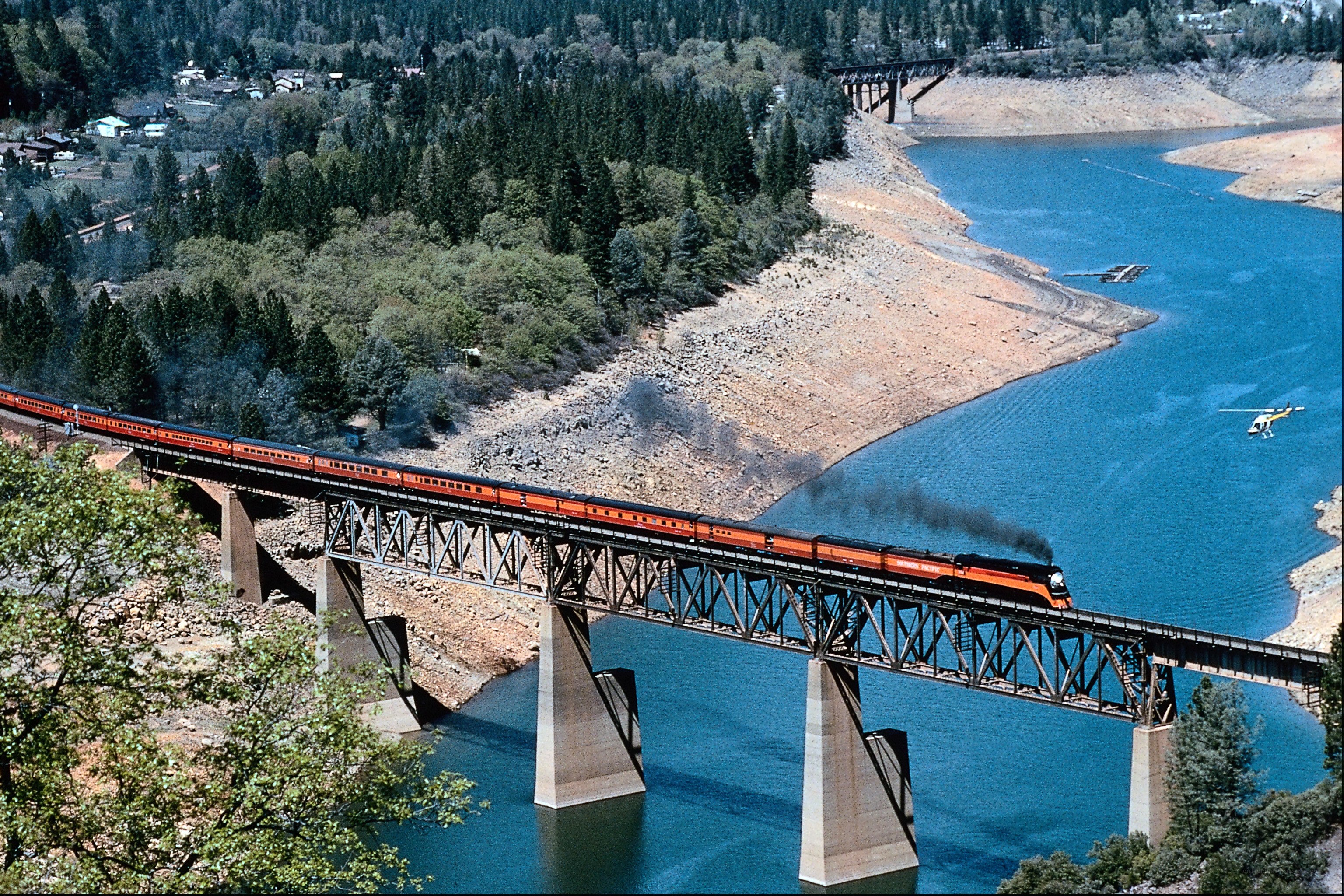 Train crossing bridge over lake