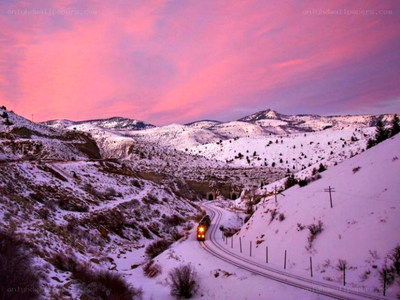 Train in snowy mountains at sunset