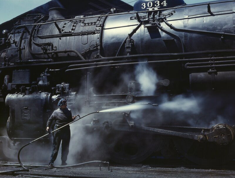 Train worker cleaning locomotive